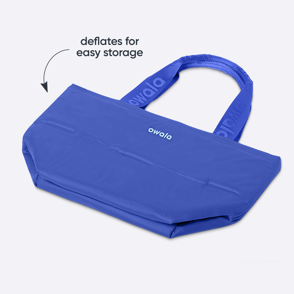 Owala Puffer Mini in Al Fresco, cobalt blue puffy tote shown flattened with matching cobalt owala-branded handles, with text reading "deflates for easy storage"