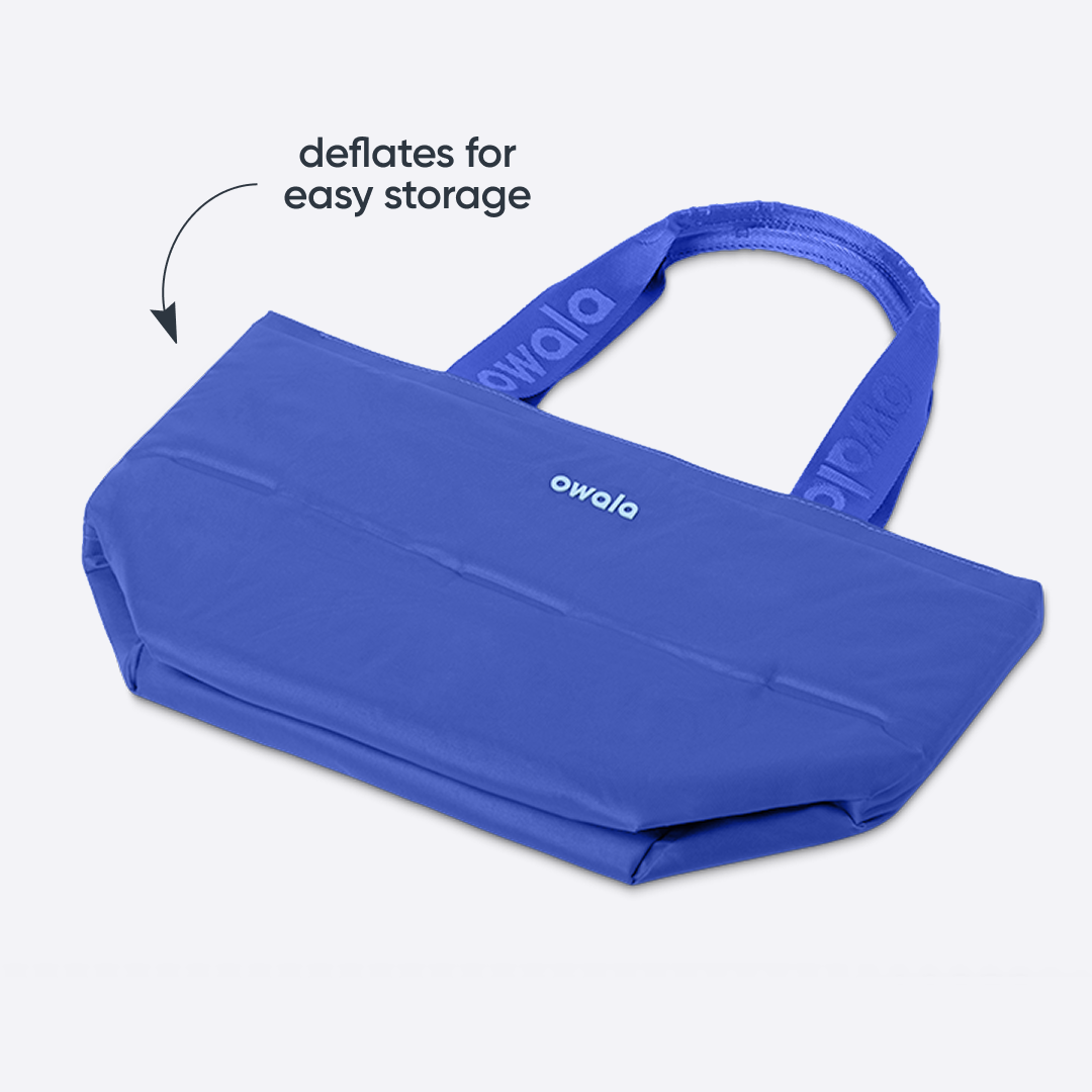 Owala Puffer Mini in Al Fresco, cobalt blue puffy tote shown flattened with matching cobalt owala-branded handles, with text reading "deflates for easy storage"