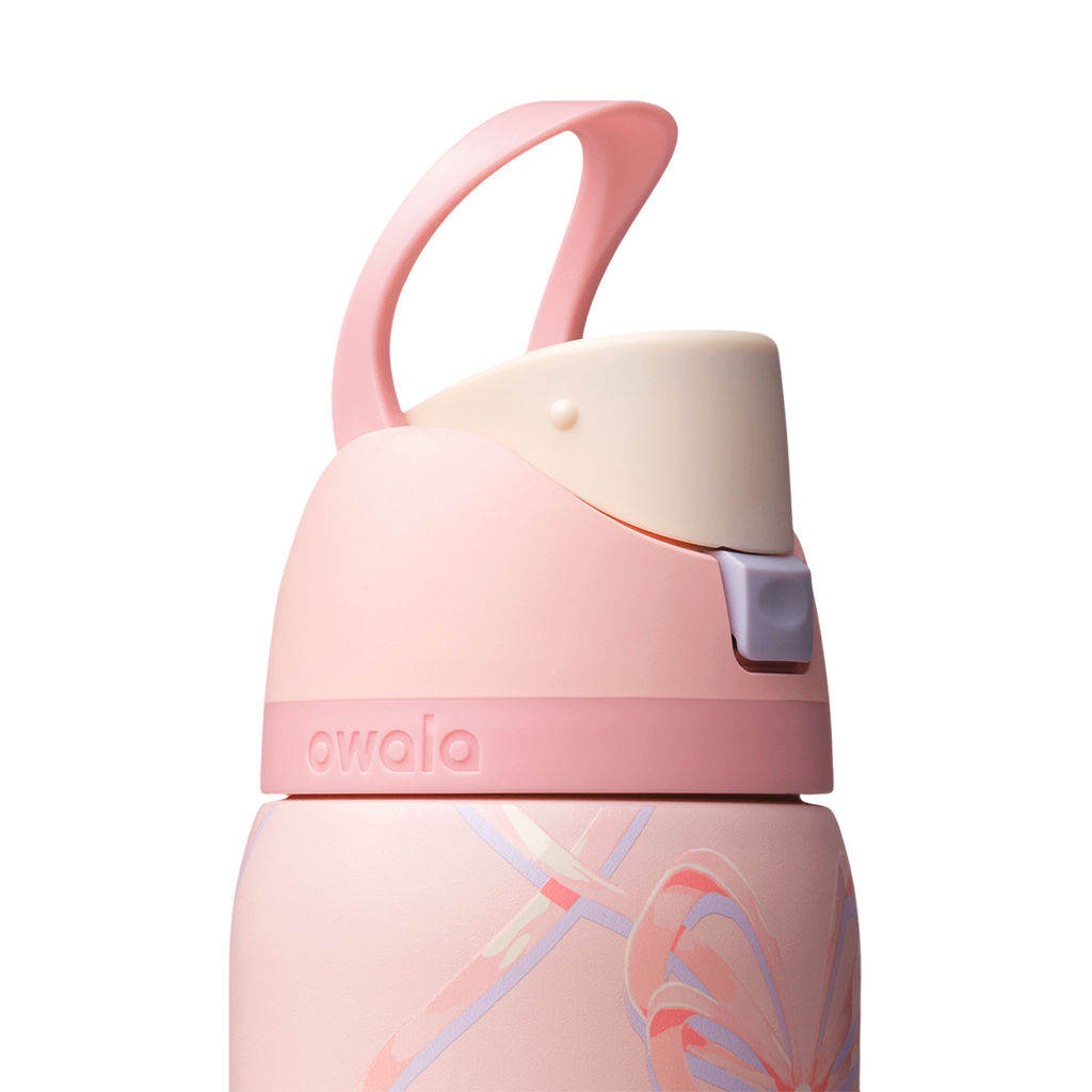 Owala FreeSip 32oz in Sugar Plum Fairy, close-up of pink lid with cream flip cap and pink carry loop raised above the bow-patterned body