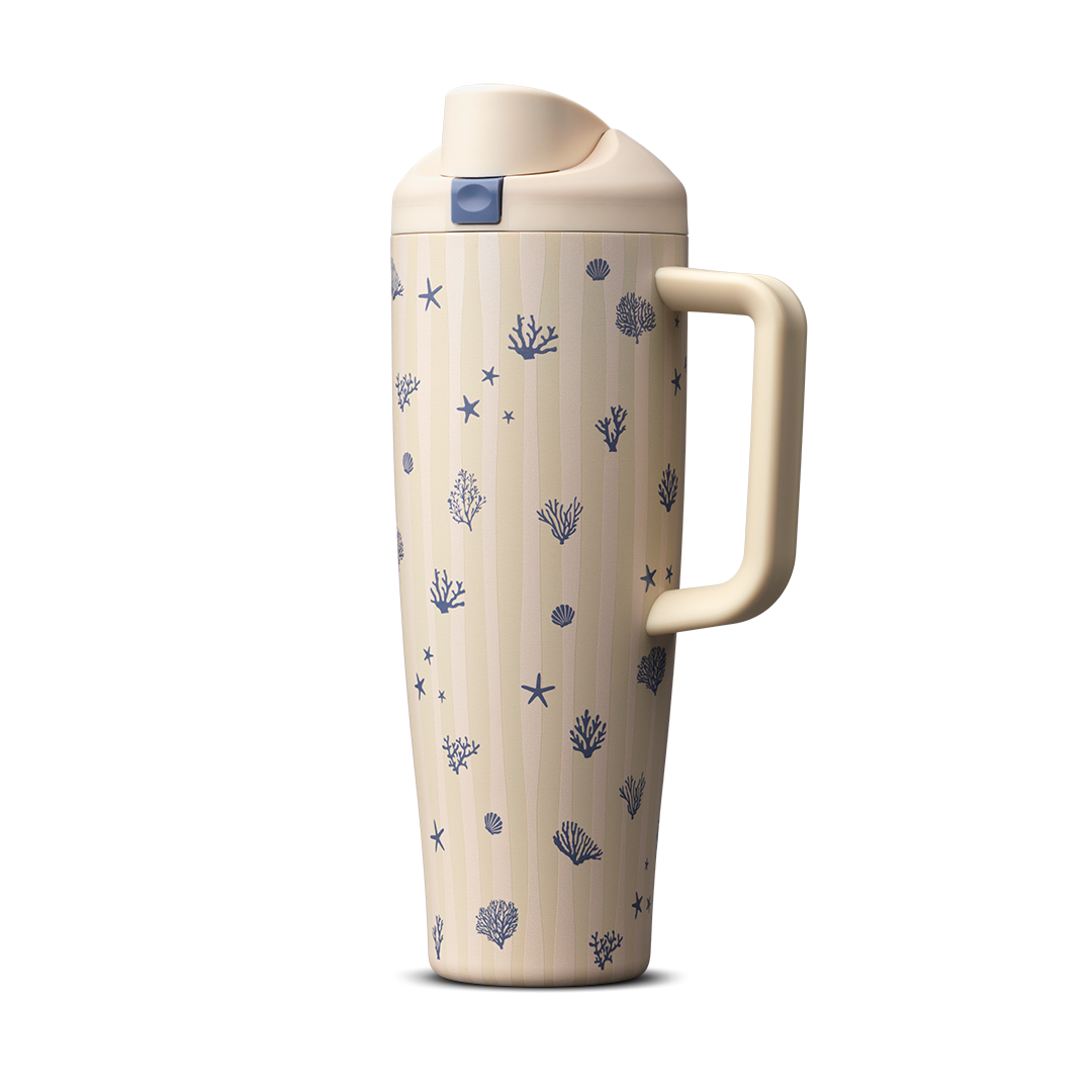 Owala FreeSip Tumbler 30oz in Coral Cabana, cream insulated stainless steel body with navy coral, starfish, and seashell pattern, matching cream flip cap, lid, and side handle with navy push-button