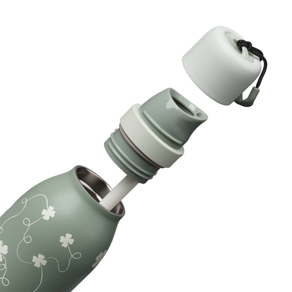Owala FreeSip Twist 24oz in Clover Achiever, exploded view showing the sage green body with white clover pattern, sage twist cap removed exposing the white FreeSip spout, and the carry string