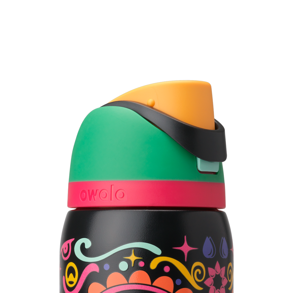Owala FreeSip Sway 32oz in Sugar Skull, lid detail showing green flip cap, orange push-button, black carry loop, and pink lid accent ring over sugar-skull patterned body; glows in the dark