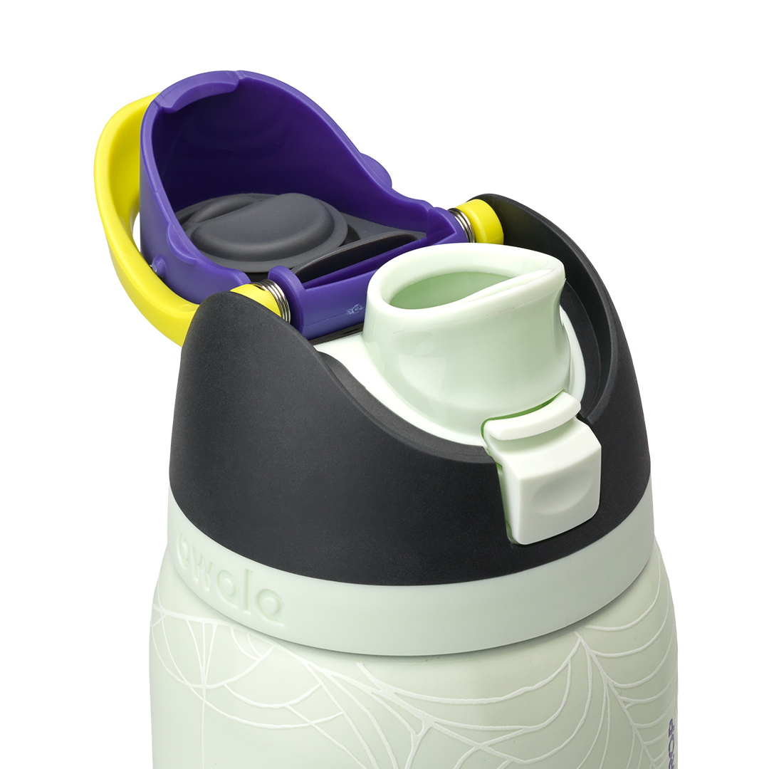 Owala FreeSip 32oz in RIP, flip cap open showing yellow-green FreeSip spout, purple lid interior with gray silicone seal, dark charcoal lid, on pale mint green body with white skeleton-hand pattern; glows in the dark