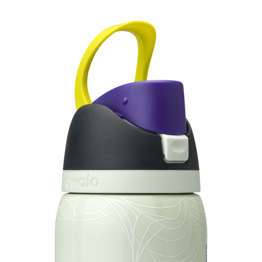 Owala FreeSip 32oz in RIP, lid detail showing dark charcoal flip cap with yellow carry loop over pale mint green body with white skeleton-hand pattern, and pale green accent ring; glows in the dark