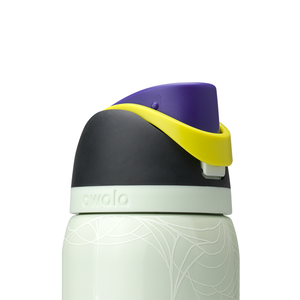 Owala FreeSip 32oz in RIP, lid detail showing dark charcoal flip cap closed, yellow carry loop, pale green accent ring on pale mint green body with skeleton-hand pattern; glows in the dark