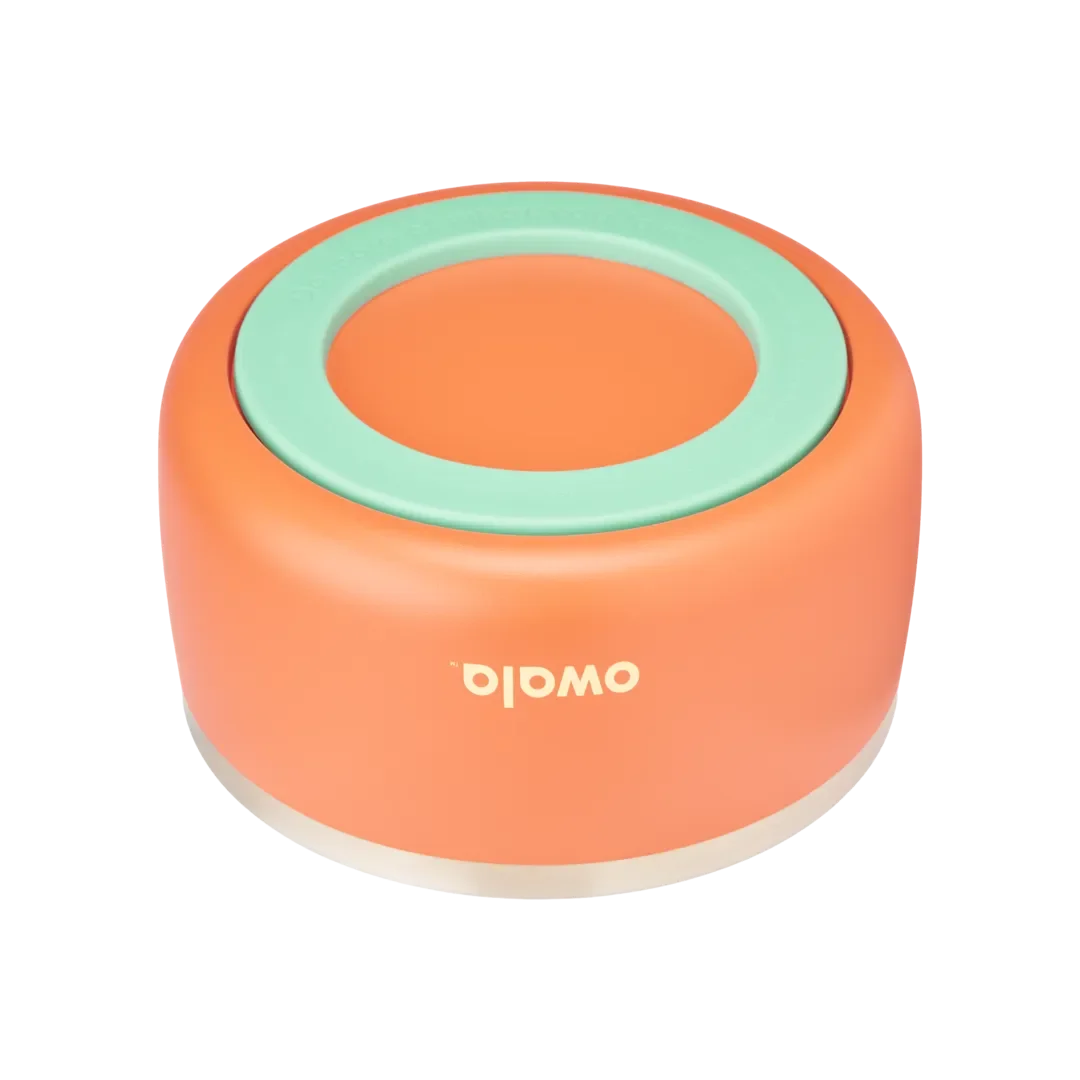 Owala Pet Bowl, bottom view showing orange silicone cup exterior with mint green accent ring embossed with "Do more of what you love" and thin stainless steel band at rim, cream Owala logo on cup side