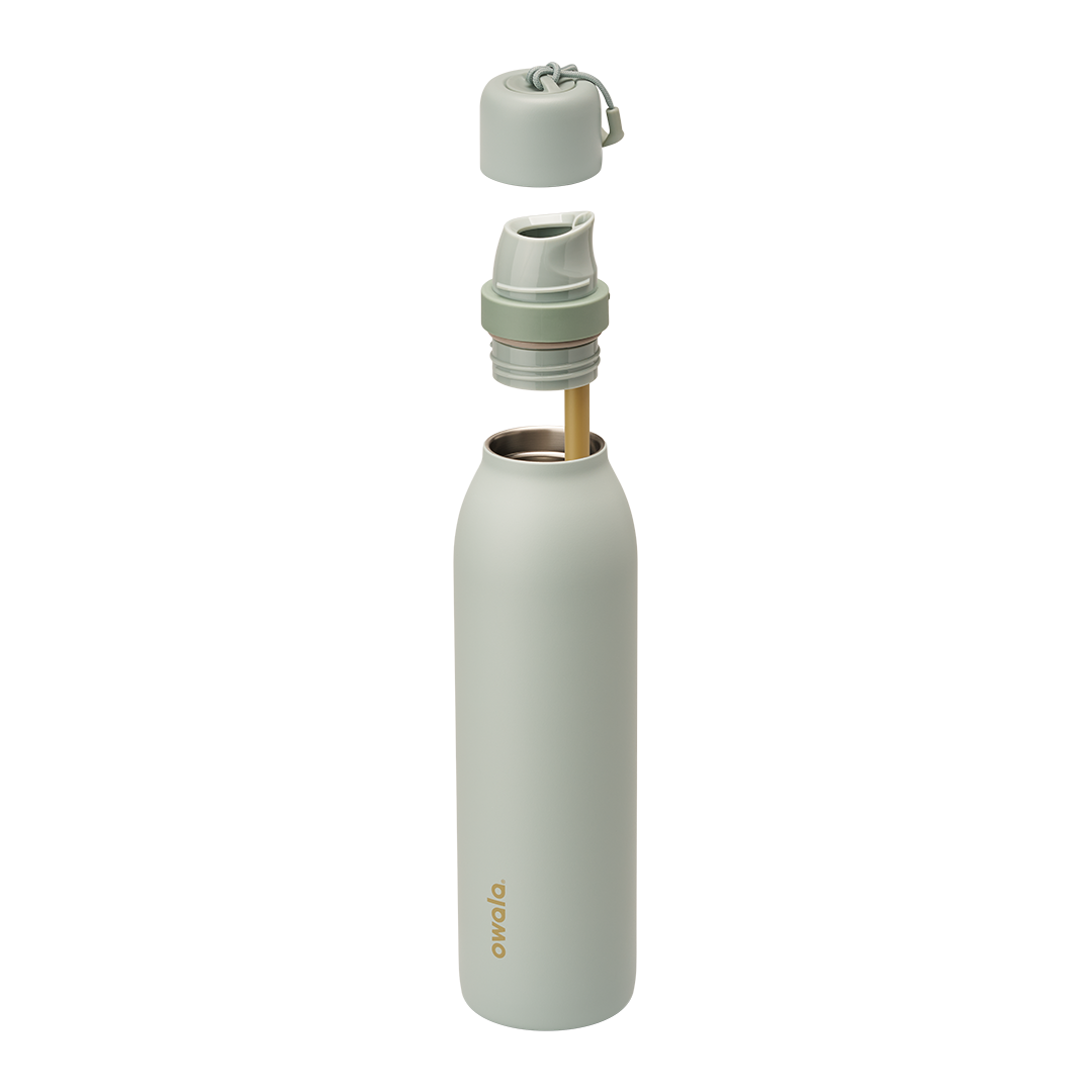 Owala FreeSip Twist 24oz in Summer Paradise, exploded view with sage green insulated stainless steel body and gold Owala logo, twist cap removed showing the FreeSip spout at the bottle opening, cap and FreeSip spout floating above with off-white carry string and carry string grip, gold-toned straw inside the body