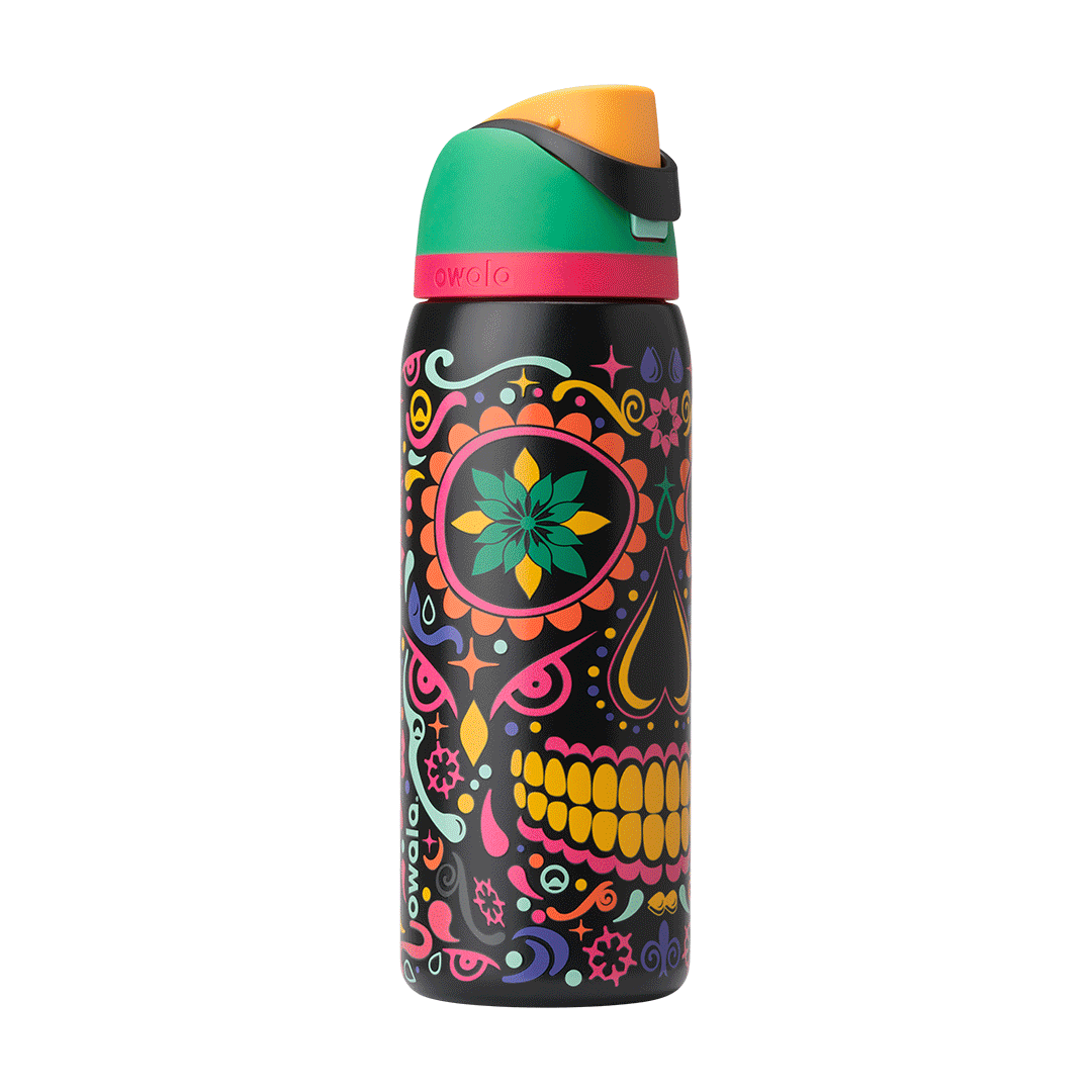 Owala FreeSip Sway 32oz in Sugar Skull, exploded view showing black body with sugar-skull pattern, green flip cap with pink accent ring, orange push-button, and red straw lifted above; glows in the dark
